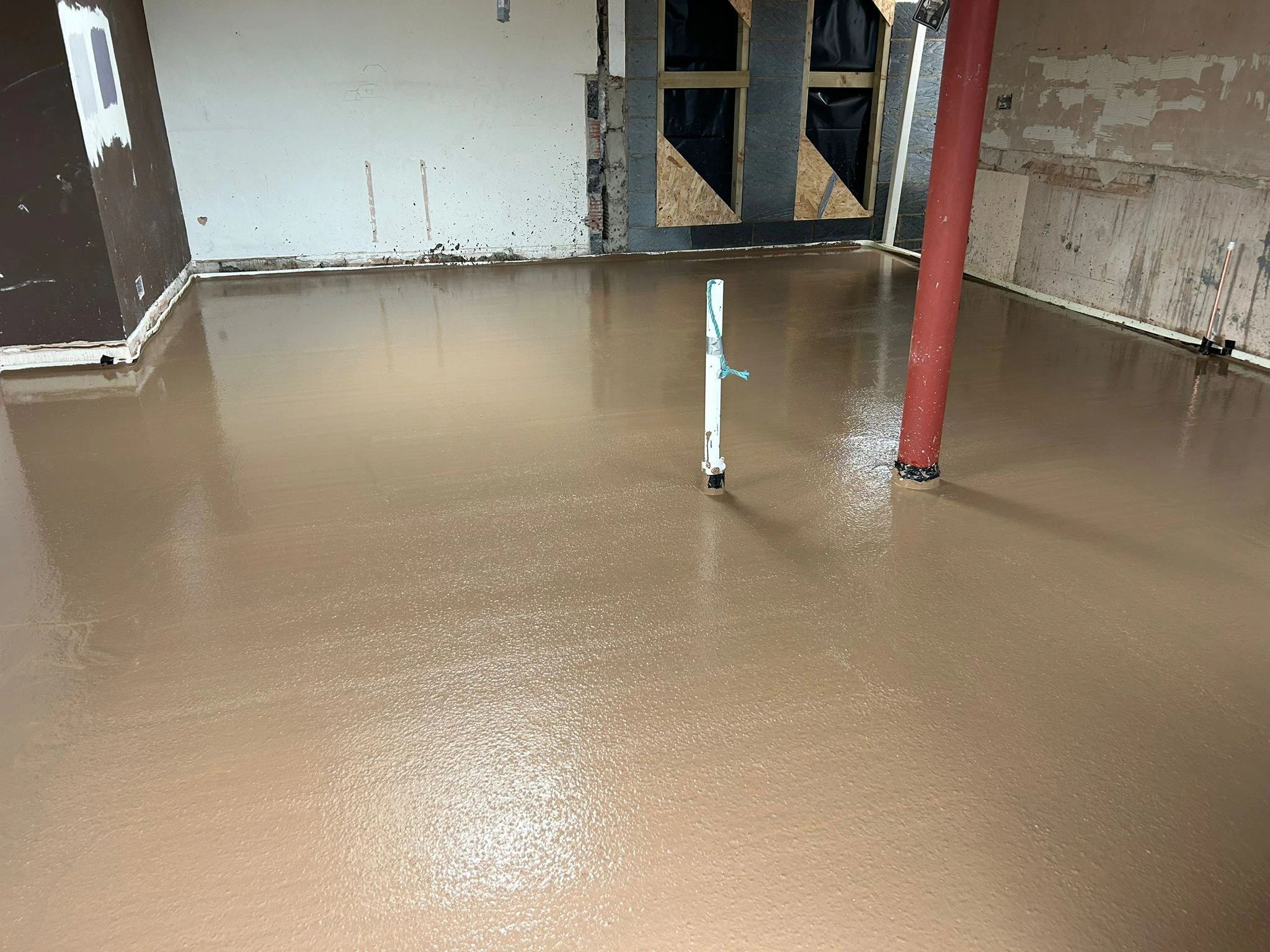 Liquid screed being poured over underfloor heating